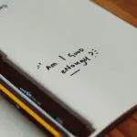 notebook with the question "Am I good enough?" written on it